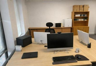 Workspace detail showing computer monitors and a wooden cabinet with a coffee machine and microwave.
