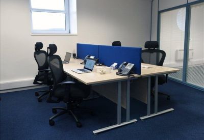 Office workspace with two desks, blue privacy screens, and ergonomic chairs.