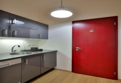 Minimalist kitchen area with red door and dark cabinets.