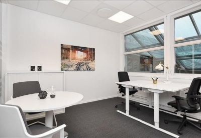 Private office with a white standing desk and a small meeting table.
