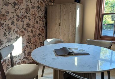 Small meeting room with round marble table and floral wallpaper.