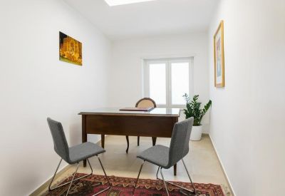 Private office featuring a classic wooden desk, gray chairs, and a small potted plant.