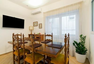 Formal dining or meeting room with a wooden table, velvet-backed chairs, and a wall-mounted TV.