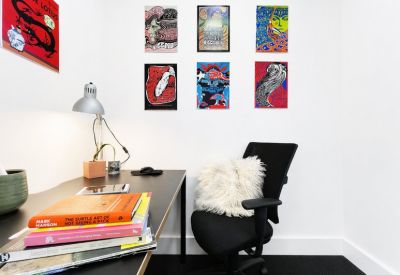 Compact office space with a dark desk and colourful pop-art posters.