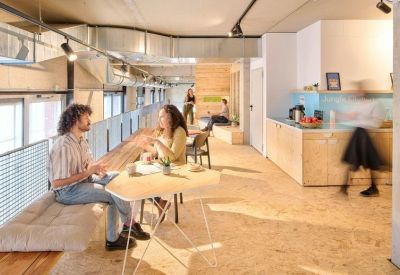 Bright communal kitchen and dining area with light wood floors and people socialising.