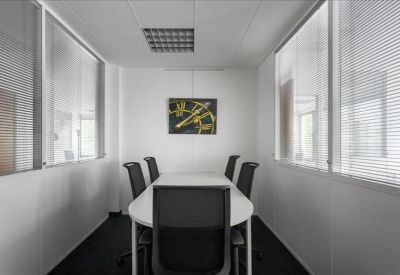 Small meeting room with a white table, black chairs, and a minimalist wall clock.