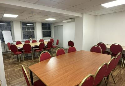 Bright conference room with a large wooden table, red chairs, and polished wood flooring.