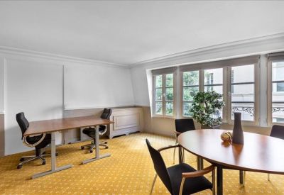 Bright office space with two wooden desks and large windows overlooking the street.