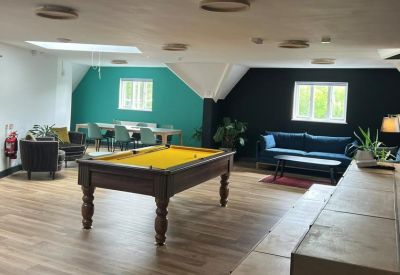 Breakout area featuring a yellow pool table, teal feature wall, and comfortable seating.