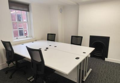 Private office suite with white desks, black mesh chairs, and an ornamental fireplace.