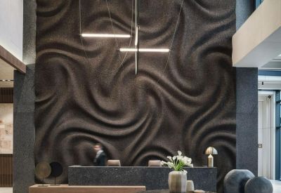 Sophisticated reception area featuring a large textured feature wall and dark marble desk.