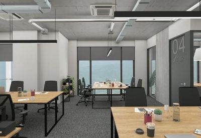 Bright open-plan office with wooden desks and black ergonomic chairs.