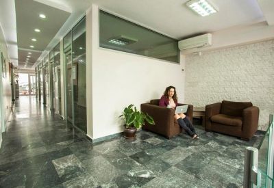 Common area lounge with dark brown armchairs and a green plant on polished stone flooring.