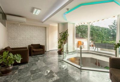 Modern reception lounge area with marble floors and views of green foliage through large windows.