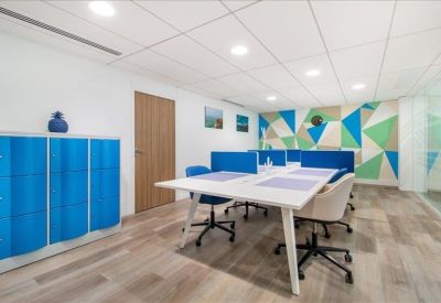 Vibrant coworking zone with blue dividers, geometric wall art, and light wood flooring.