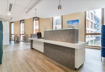 Sleek reception area with a minimalist stone-finish desk and wide windows showing city views.