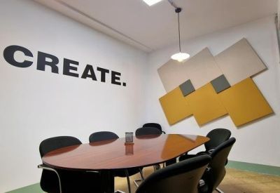 Meeting room with an oval wooden table and CREATE wall graphic.