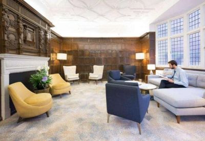 Elegant lounge area with wood-paneled walls, a classic fireplace, and plush blue and yellow armchairs.