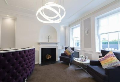 Bright reception area featuring a purple tufted desk and modern ring chandelier.