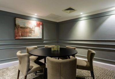 Meeting room with a round black table and grey upholstered chairs.