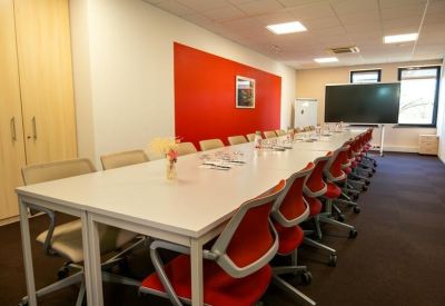 Long conference room with a red accent wall and a large digital screen.