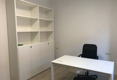 Clean office interior with a white desk, black ergonomic chair, and a large storage cabinet.