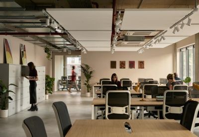 Busy coworking lounge with white lockers and plants near the workspace.