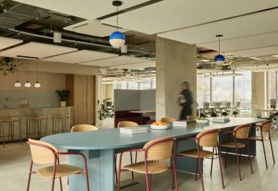 Bright communal kitchen and breakout area with a blue oval table and colourful pendant lights.