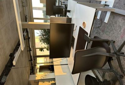 Bright workspace featuring white desks, dual monitors, and office chairs.