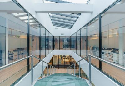 Modern glass-walled atrium and staircase with a view of internal office floors.