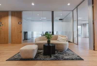 Bright reception lounge with a curved beige sofa on a patterned rug.