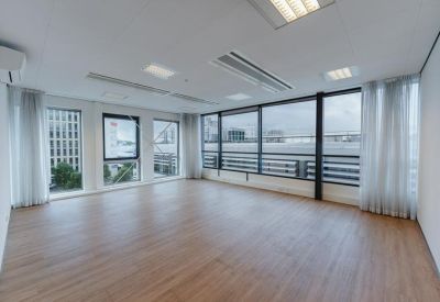 Spacious open-plan office with wood flooring and large windows overlooking the city.