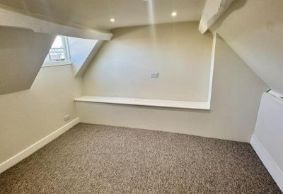 Neutral attic office suite with slanted walls and a built-in white ledge.