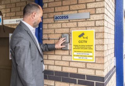Secure keypad entrance with CCTV signage and brick wall.
