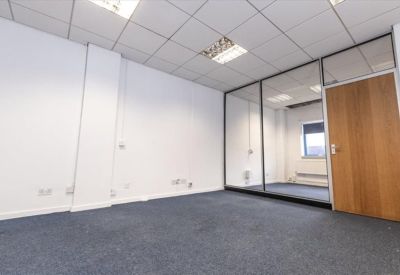 Spacious empty office suite with blue carpet and glass partitions.