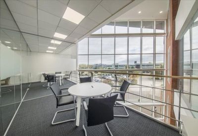 Glass-walled breakout area with a circular table overlooking the atrium.