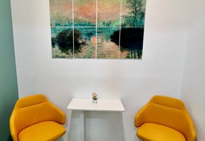 Private breakout nook with two yellow armchairs and Impressionist-style wall art.