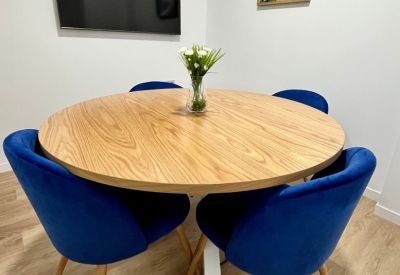 Meeting area with a round wooden table and vibrant blue velvet chairs.