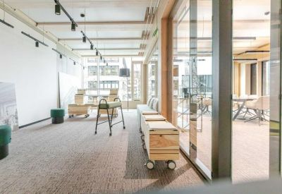Flexible workspace with wooden storage units and stool seating by a large window.