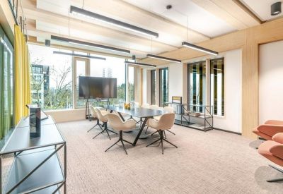Spacious meeting room with a long dark table, modern chairs, and a large wall-mounted screen.