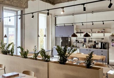 Bright communal dining area and kitchen with wooden tables and stone ceilings.