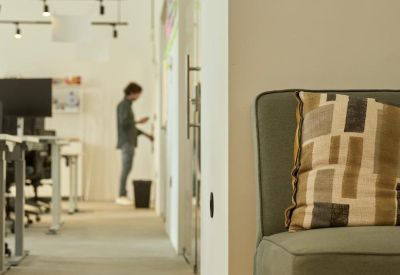 Open-plan coworking area with a person working and a plush green armchair.