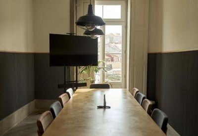 Long wooden meeting table in a boardroom with dark accent walls and pendant lighting.
