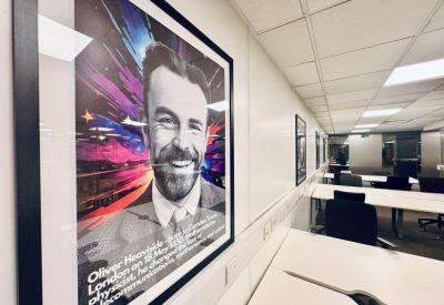 Close-up of a framed artistic portrait on an office wall near workstations.