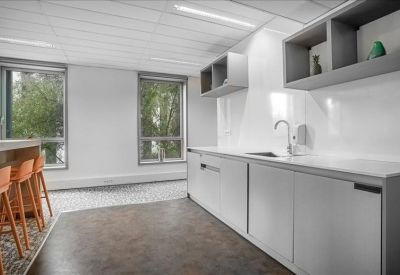 Sleek white kitchenette area with grey cabinetry and breakfast bar seating.