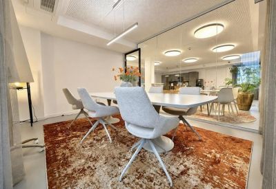 Sleek conference room with a large white table, plush grey chairs, and a textured rug.