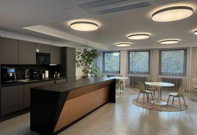 Modern office kitchen with dark cabinetry, a breakfast bar, and casual dining tables.