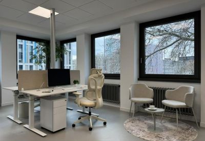 Bright workspace featuring white desks and comfortable armchairs on a round area rug.