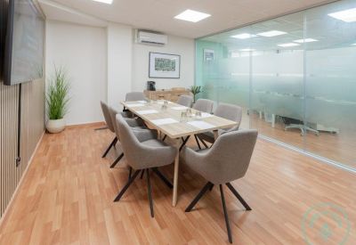 Meeting room with grey upholstered chairs and a glass partition wall.