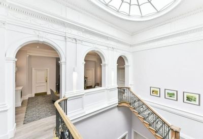 Bright white landing with arched openings, a glass skylight, and a decorative staircase.